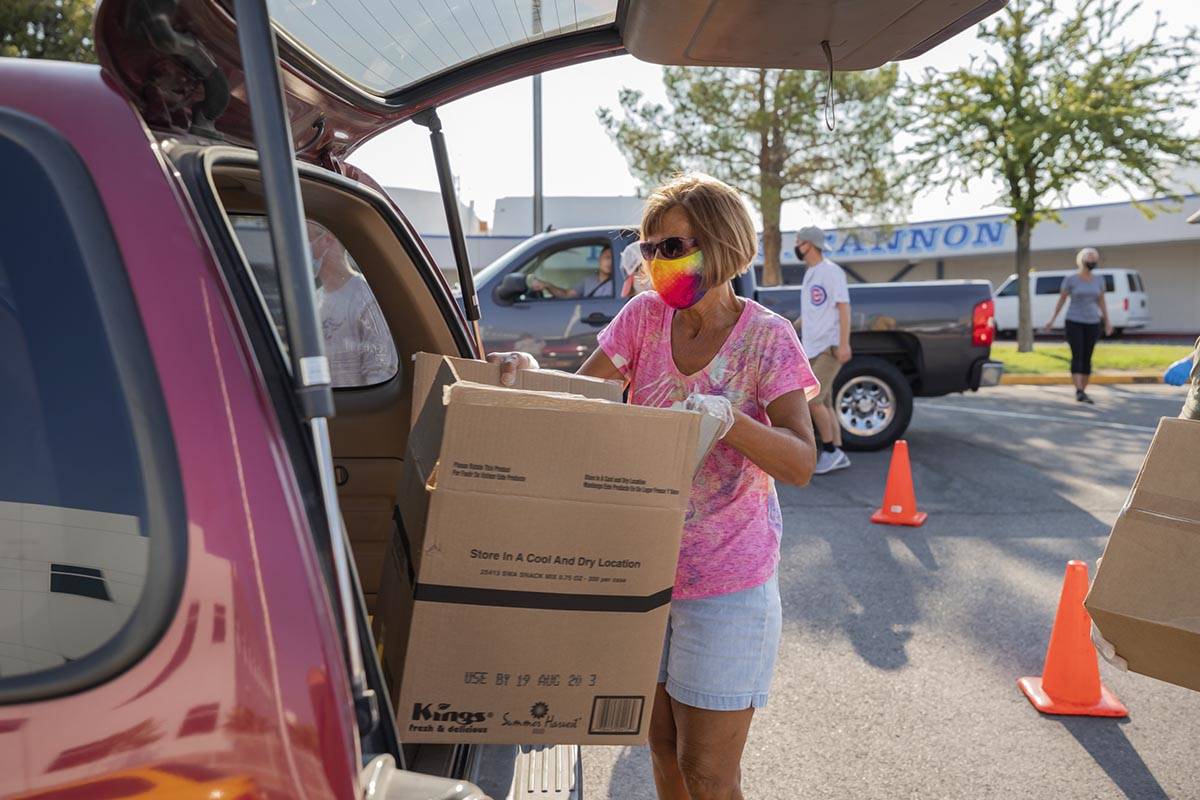 Three Square Food Bank volunteer Julie Sues-Delaney loads a vehicle going through the drive-thr ...