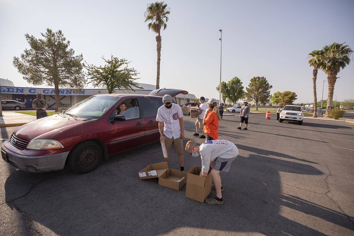 Three Square Food Bank volunteers grab the remaining food items for a vehicle going through the ...