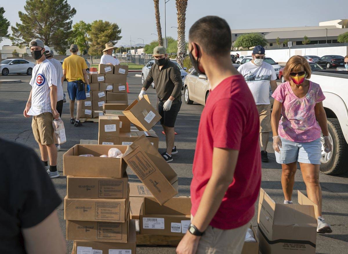 Volunteers with Three Square Food Bank distribute meals at Cannon Junior High School for the co ...