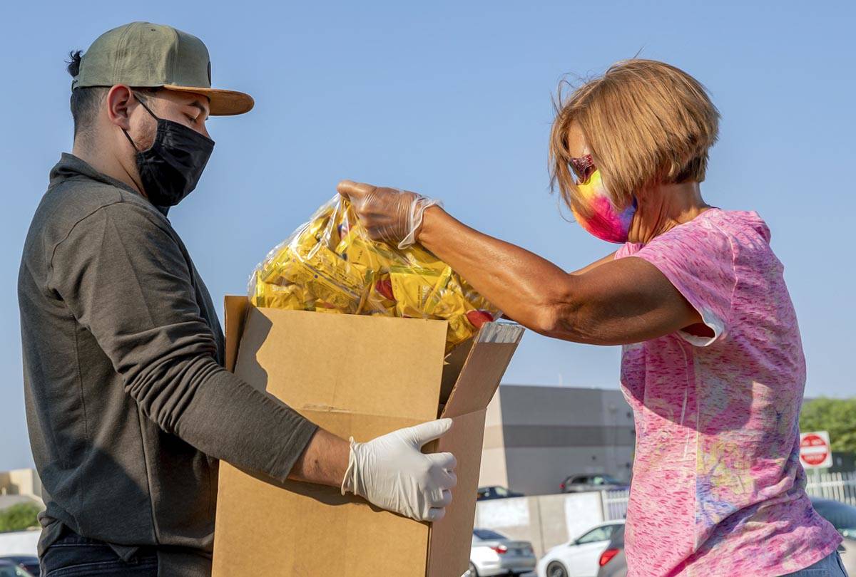 Miguel Landabazo, left, and Julie Sues-Delaney, volunteers with Three Square Food Bank, pack a ...