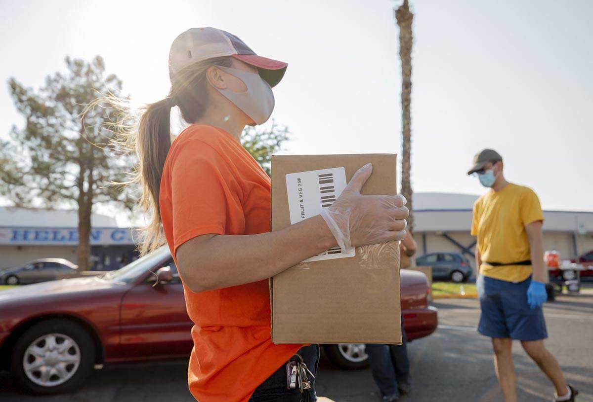 Three Square Food Bank volunteer Dinis Adams of Las Vegas distributes meals at Cannon Junior Hi ...