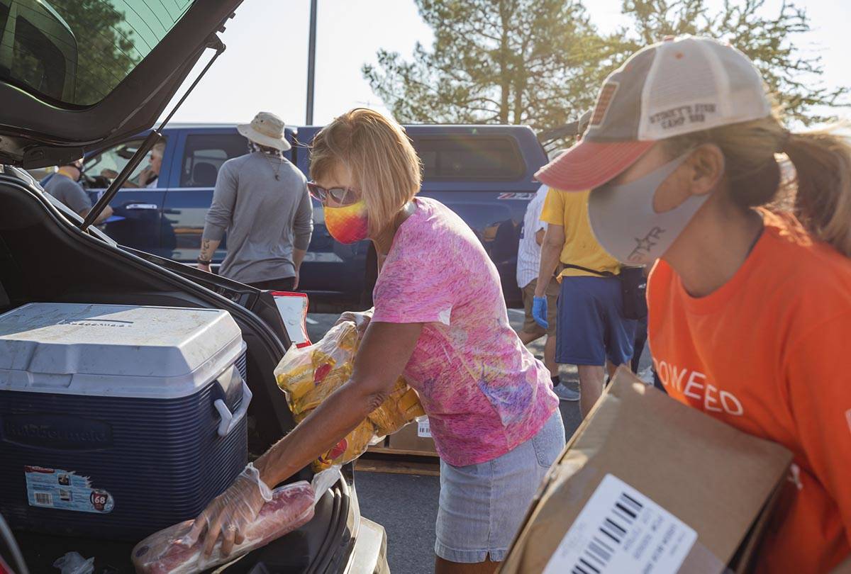 Three Square Food Bank volunteers Julie Sues-Delaney, left, and Dinis Adams load a vehicle goin ...