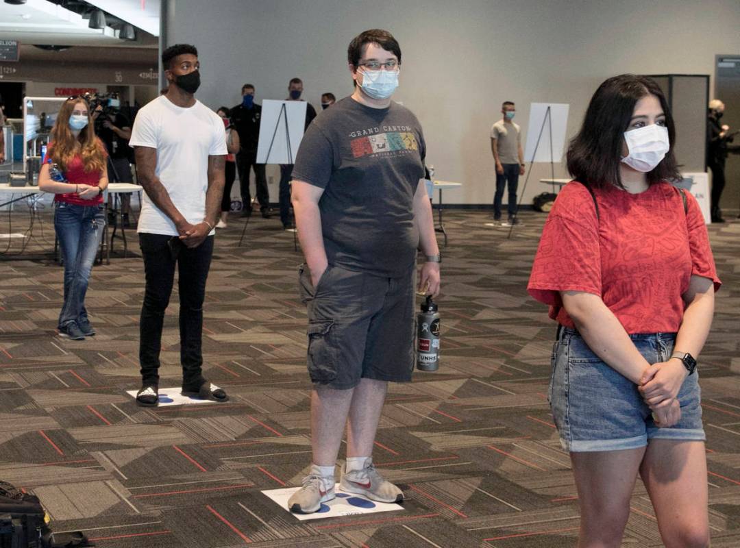 Volunteers, including Jasmine Barrett, right, and Sergio Bustos, second right, stand in line at ...
