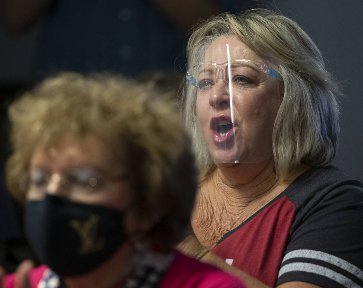 Cathy Hoolihan of Las Vegas wears a face shield as she claps and cheers at the screen as the Re ...