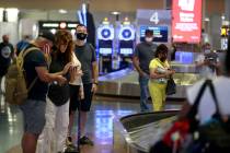 People wait for their bags at baggage claim in Terminal 1 at McCarran International Airport in ...