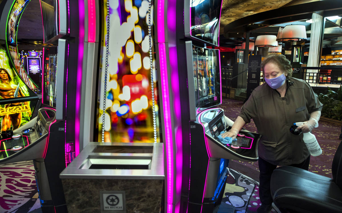 Employee Gloria Acuna sanitizes another slot machine as guests arrive as the Mirage reopens fol ...