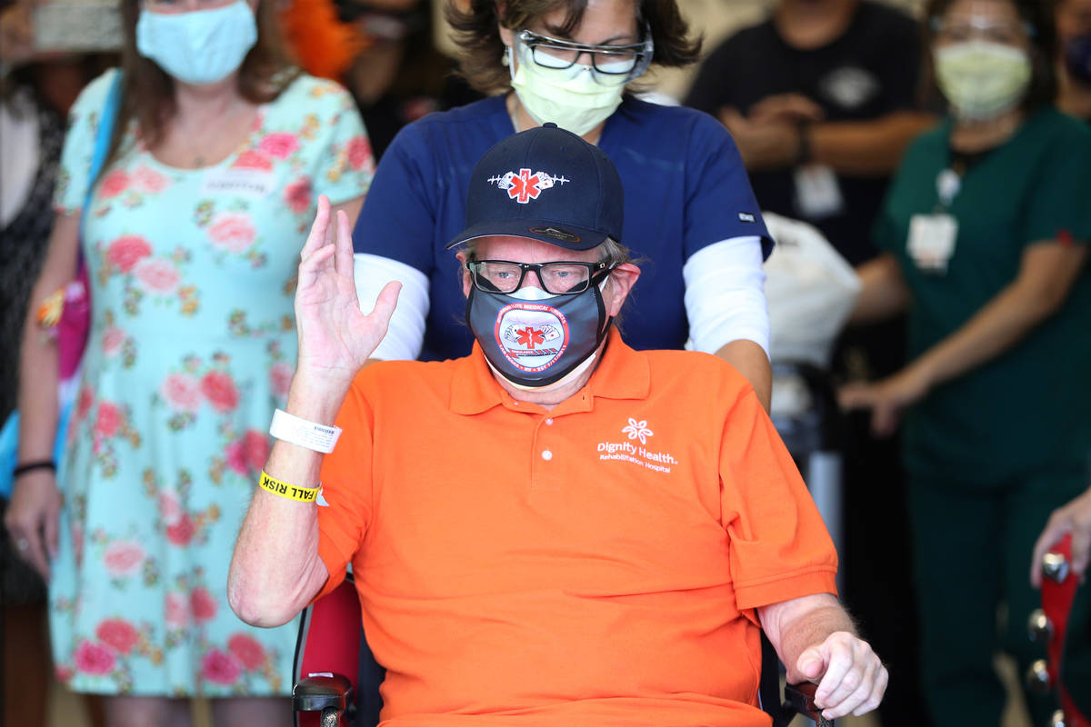 Paramedic John Foster, center, a recovered COVID-19 patient, is wheeled out by Registered Nurse ...