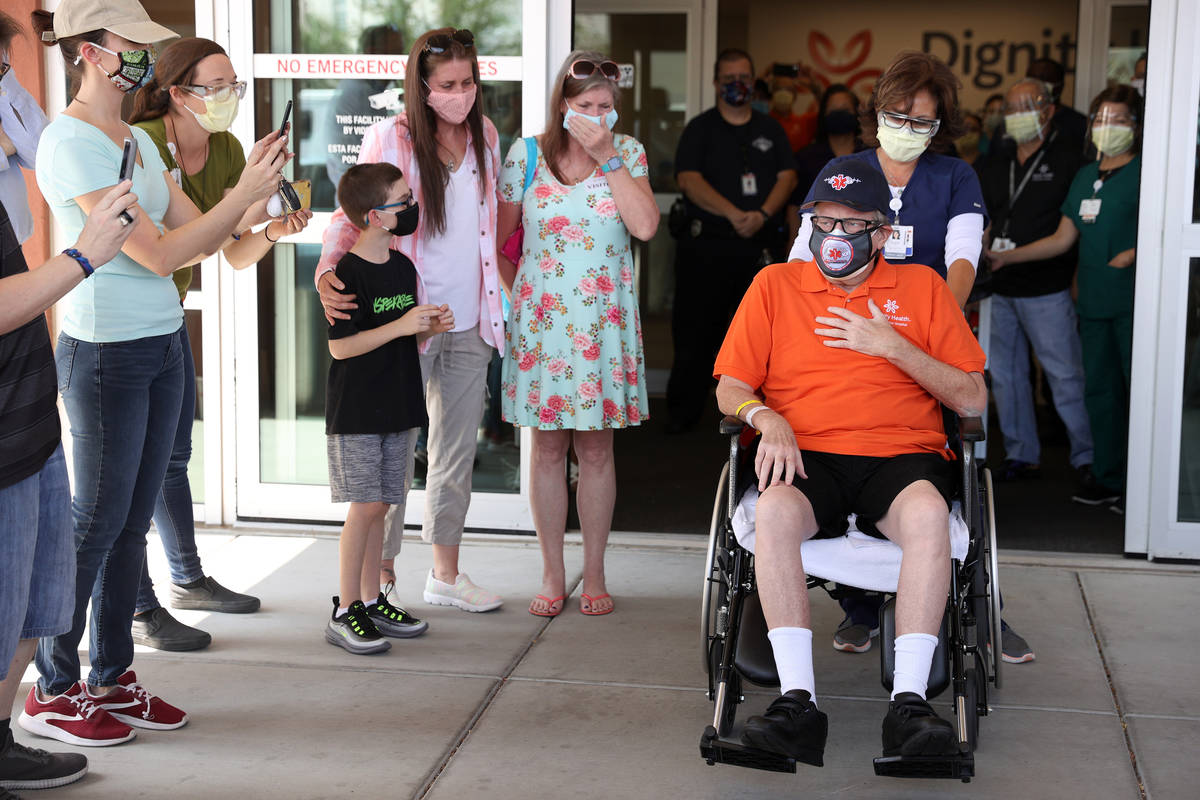 Paramedic John Foster, center, a recovered COVID-19 patient, is wheeled out by Registered Nurse ...