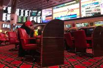 An employee wipes down chairs with Clorox wipes at Wynn Race & Sports Book on Friday, March ...