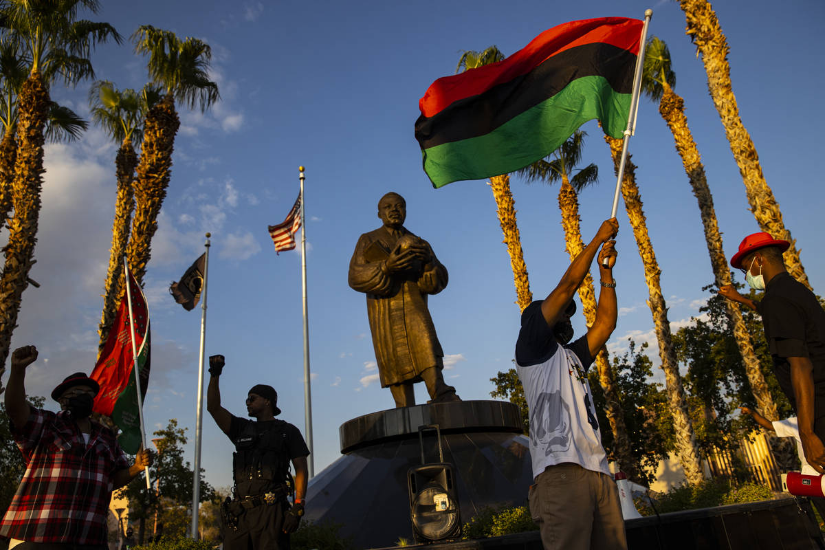 Otis Lang, of Las Vegas, right, waves a flag during the Black national anthem at a rally agains ...