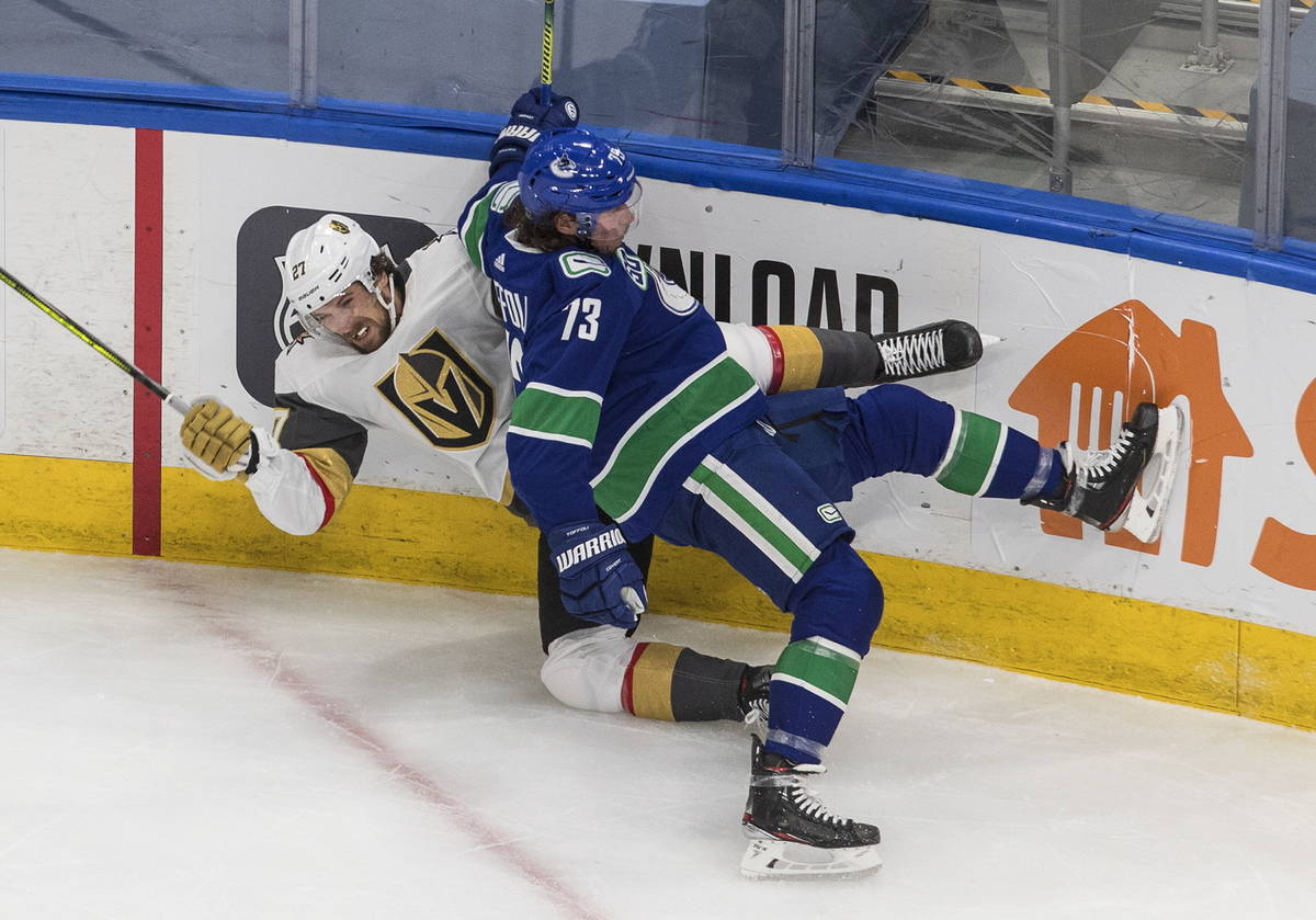 Vegas Golden Knights' Shea Theodore (27) is checked by Vancouver Canucks' Tyler Toffoli (73) du ...