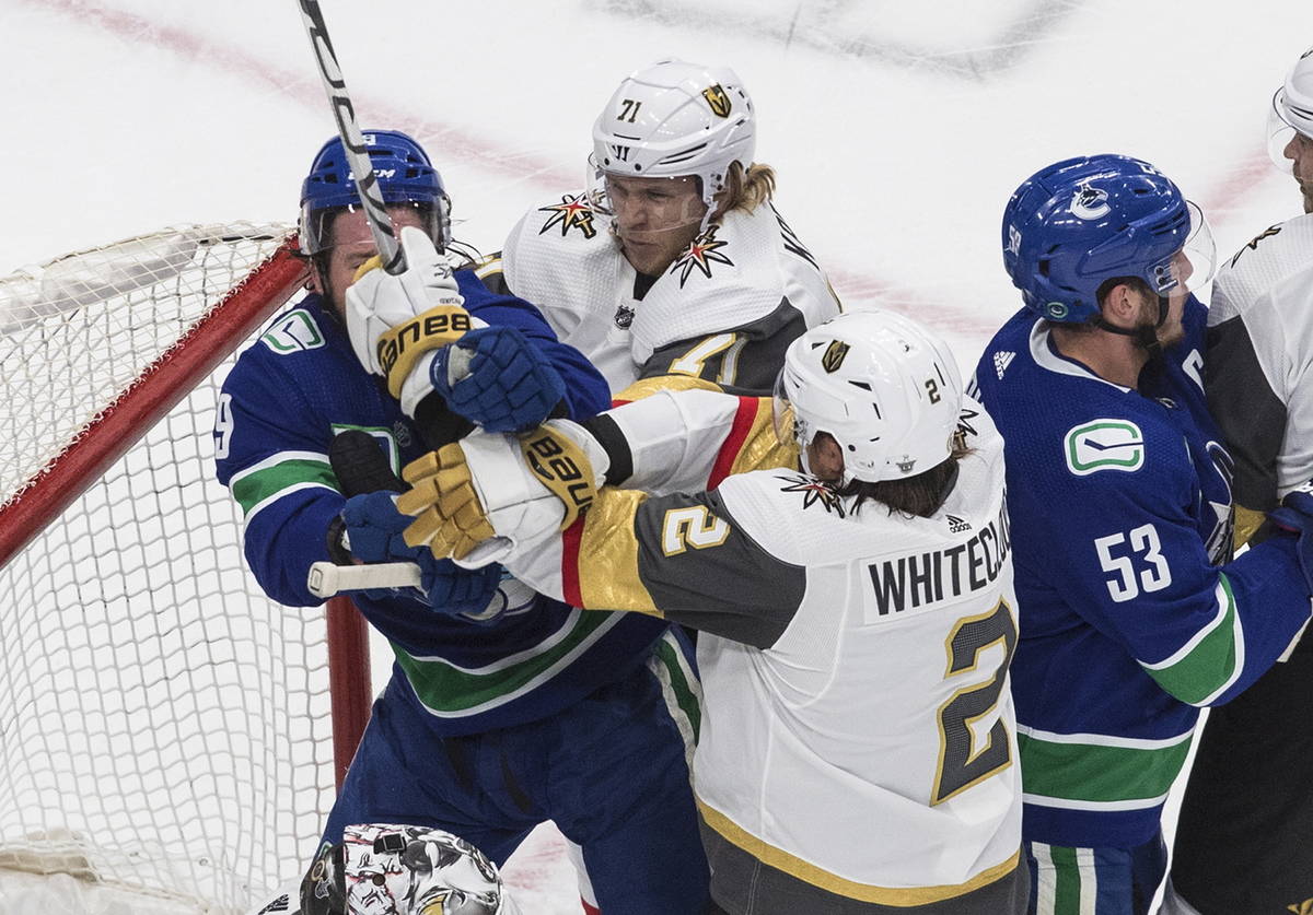 Vegas Golden Knights' Zach Whitecloud (2) and Vancouver Canucks center J.T. Miller (9) rough it ...