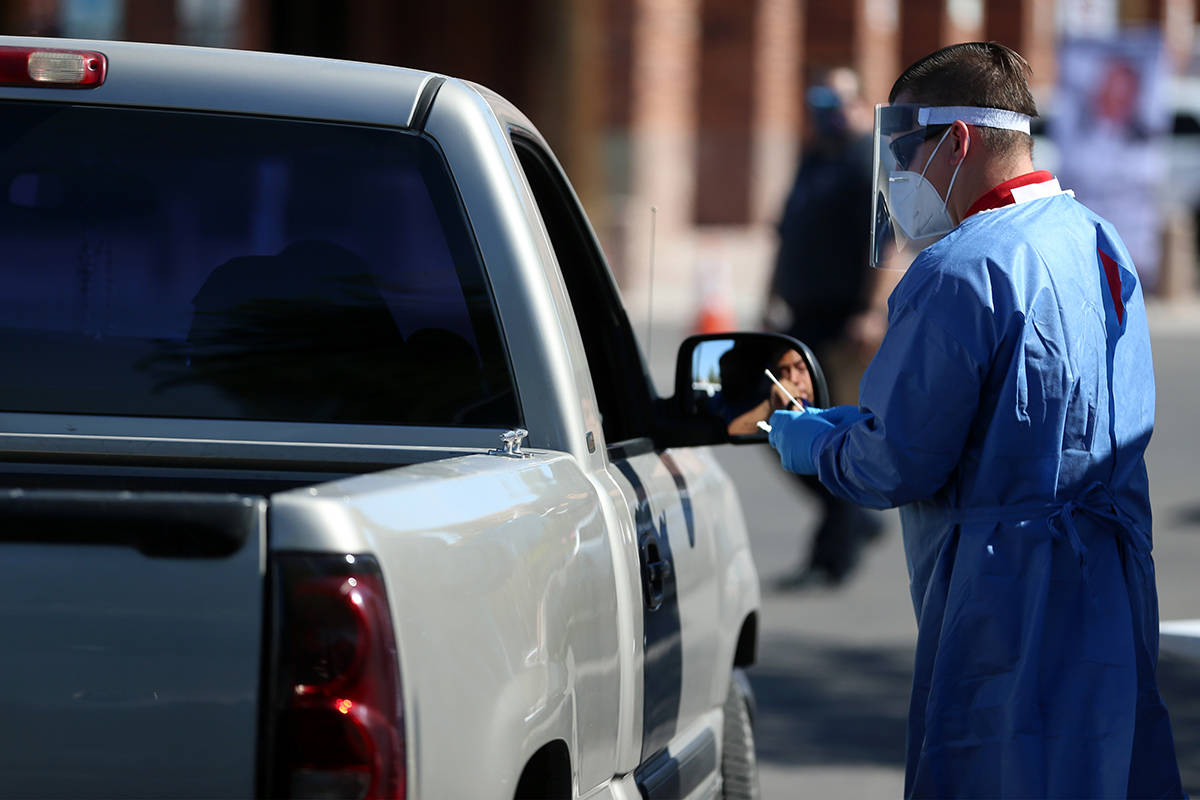 A medical worker tests a patient for COVID-19 during an event hosted by Clark County Commission ...