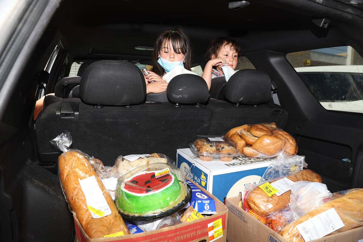 Zamira, 5, and her sister Zeriah Basulto, 5, of Las Vegas, looks at food their family received ...