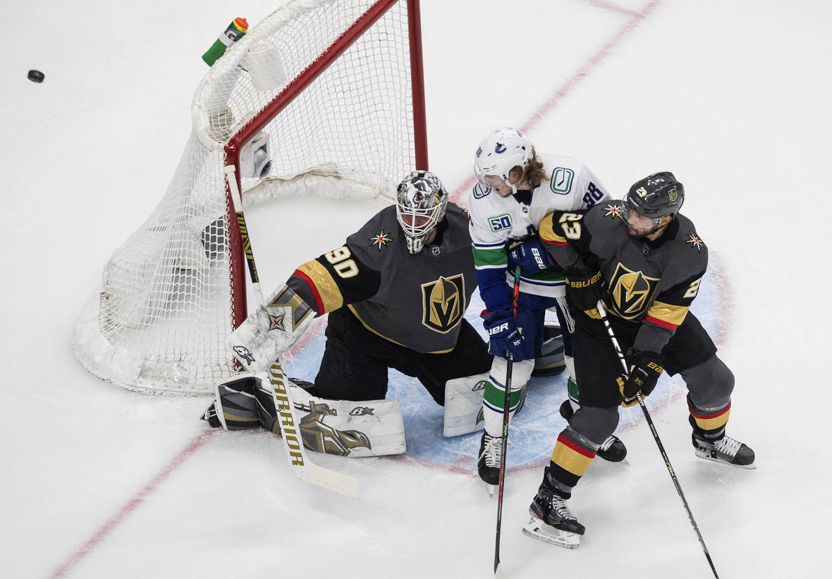 Vancouver Canucks' Adam Gaudette (88) and Alec Martinez (23) battle in front as Vegas Golden Kn ...