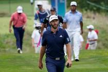 Dustin Johnson walks on the 13th fairway in front of Hideki Matsuyama, of Japan, top right, dur ...