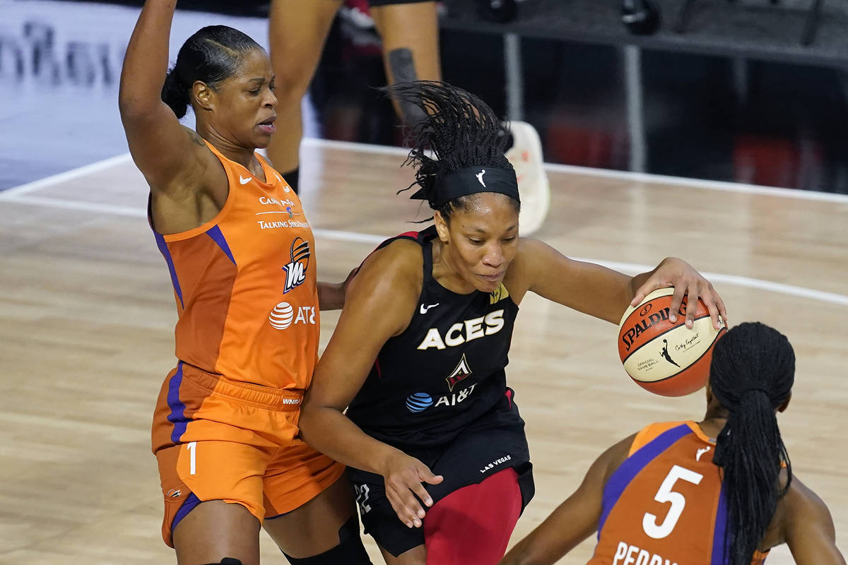 Las Vegas Aces center A'ja Wilson (22) drives between Phoenix Mercury center Kia Vaughn (1) and ...