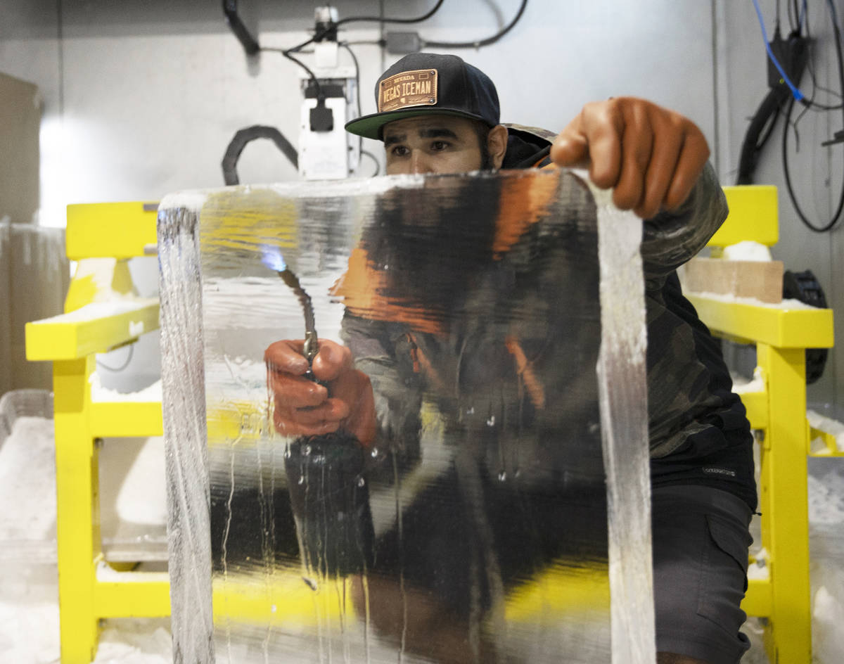 Marco Villarreal, known as "Vegas Ice Man," uses a torch to prep a fresh ice block on ...