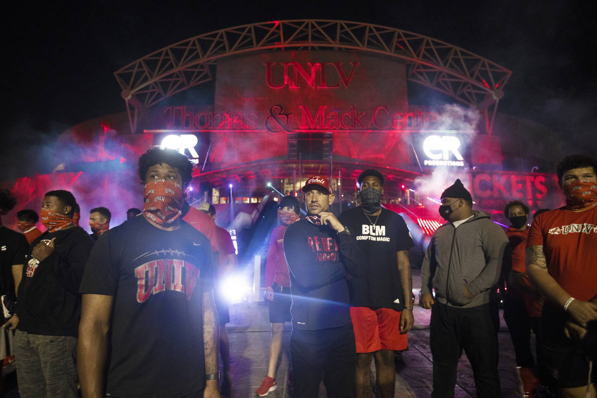UNLV head football coach Marcus Arroyo, middle, stands in front of a glowing red Thomas and Mac ...