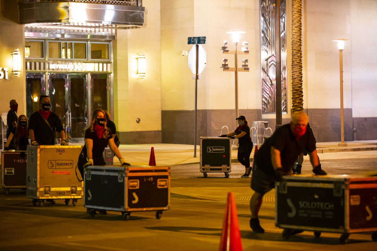 Entertainment workers push road cases around The Smith Center as it turns red for the "Red ...