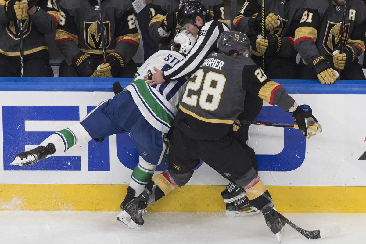 Vegas Golden Knights' William Carrier (28) and Vancouver Canucks' Troy Stecher (51) run into an ...
