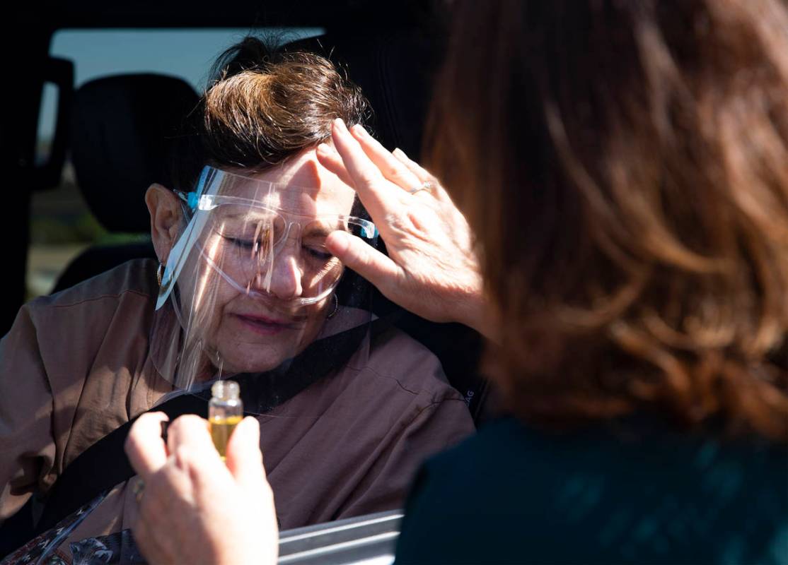 Minister Shannon Anwar gives an oil blessing to Shelle McIntyre at Sunday drive-through Communi ...