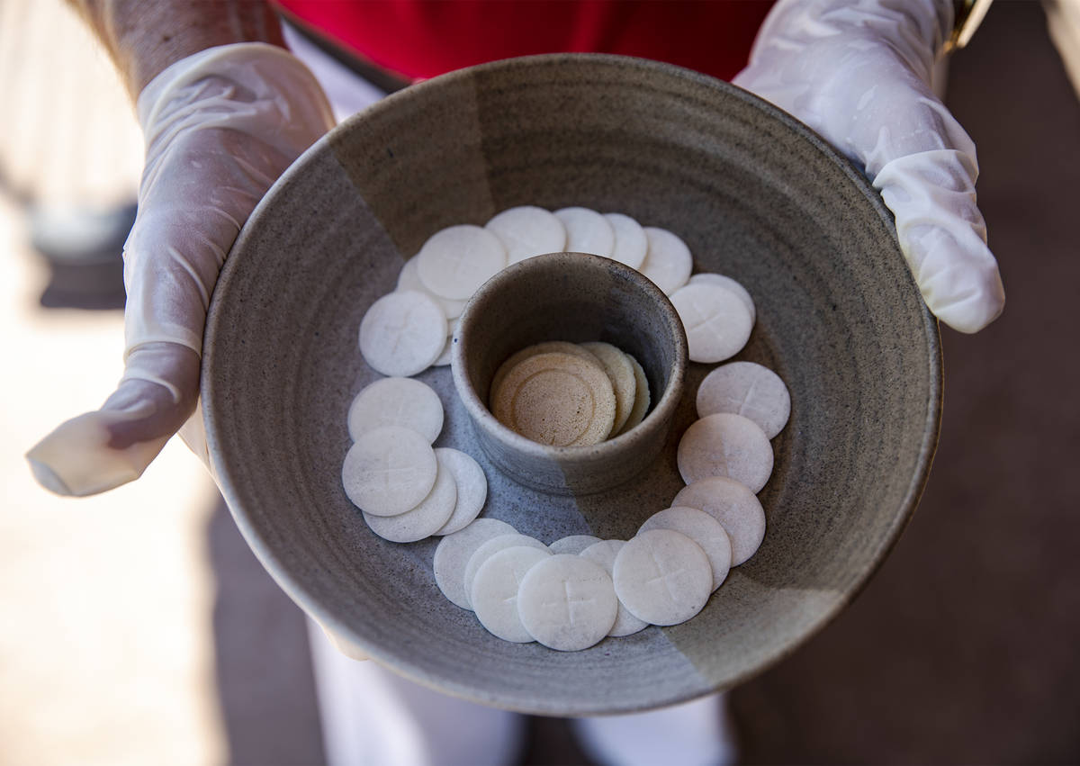 Pastor David Miller holds a plate of Communion wafers that will be used during a drive-through ...