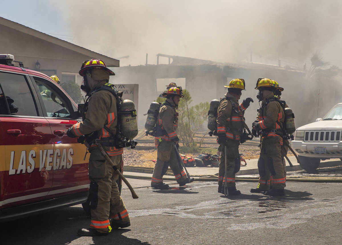 Las Vegas firefighters gather to talk as they battle a house fire on 5400 block of West Pebble ...