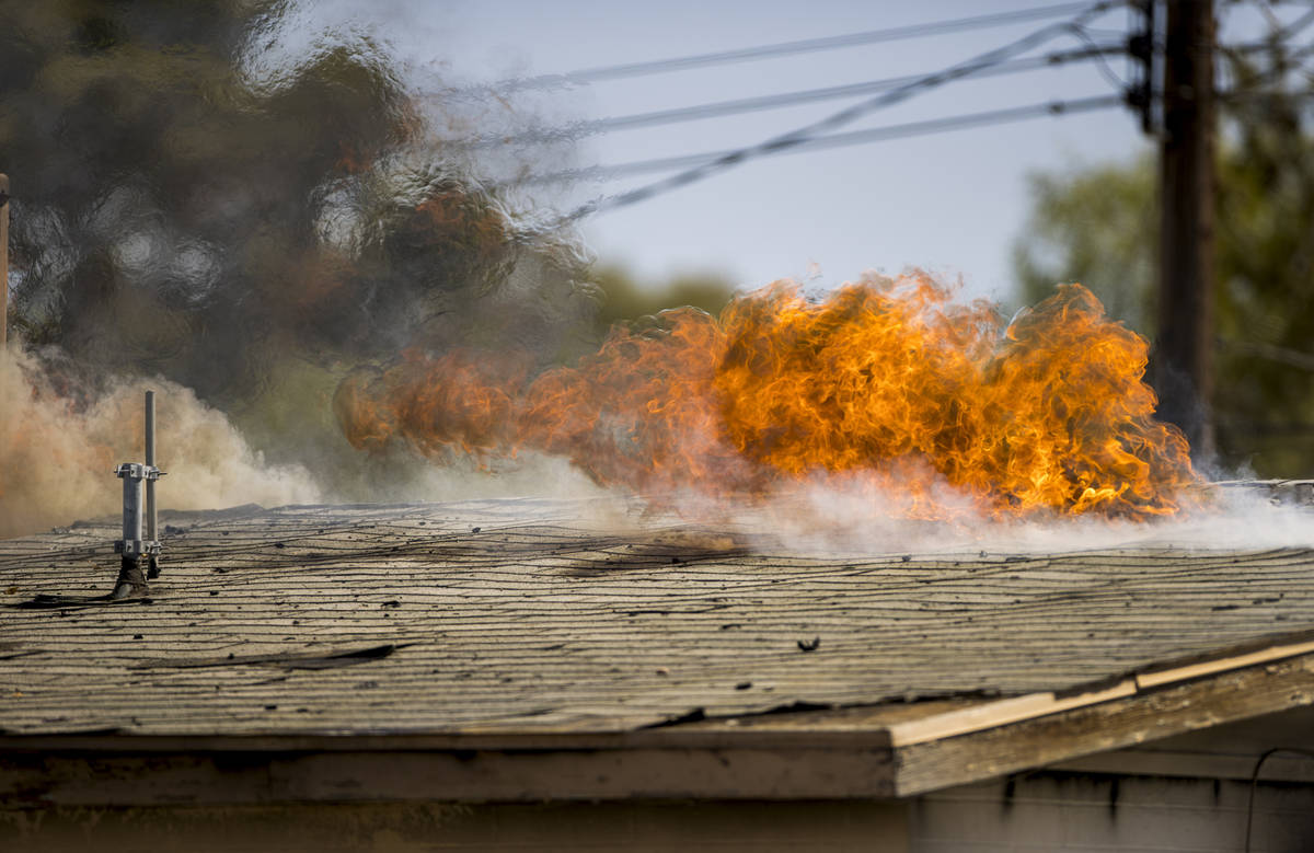 Fire burns through the roof as Las Vegas firefighters battle a house fire on 5400 block of West ...