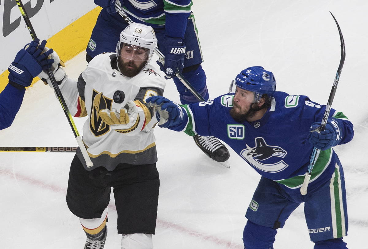 Vancouver Canucks' J.T. Miller (9) and Vegas Golden Knights' Alex Tuch (89) reach for the puck ...