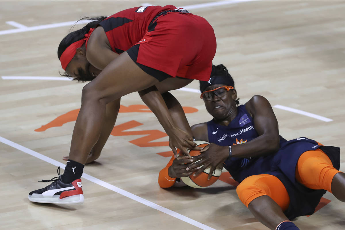 Connecticut Sun's Essence Carson, right, reaches for a ball underneath Las Vegas Aces' Jackie Y ...