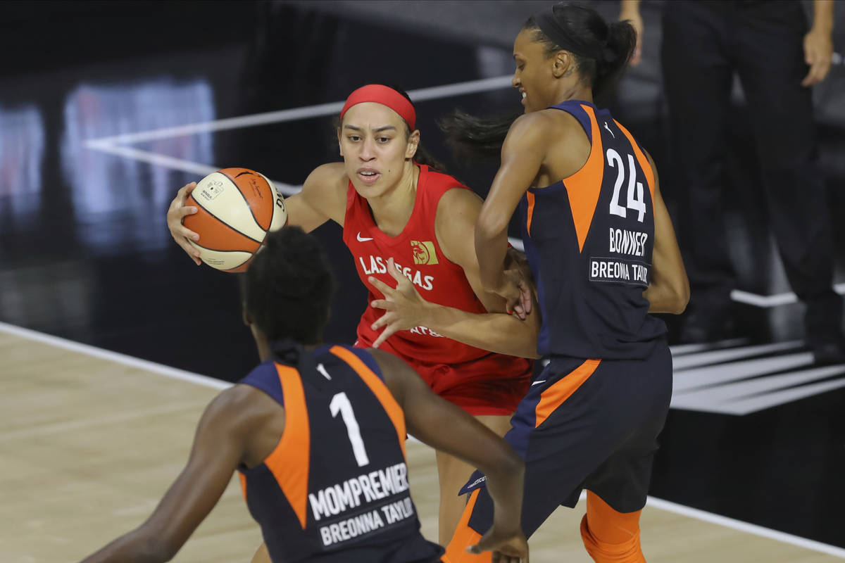 Las Vegas Aces' Dearica Hamby, center, drives against Connecticut Sun's DeWanna Bonner (24) and ...