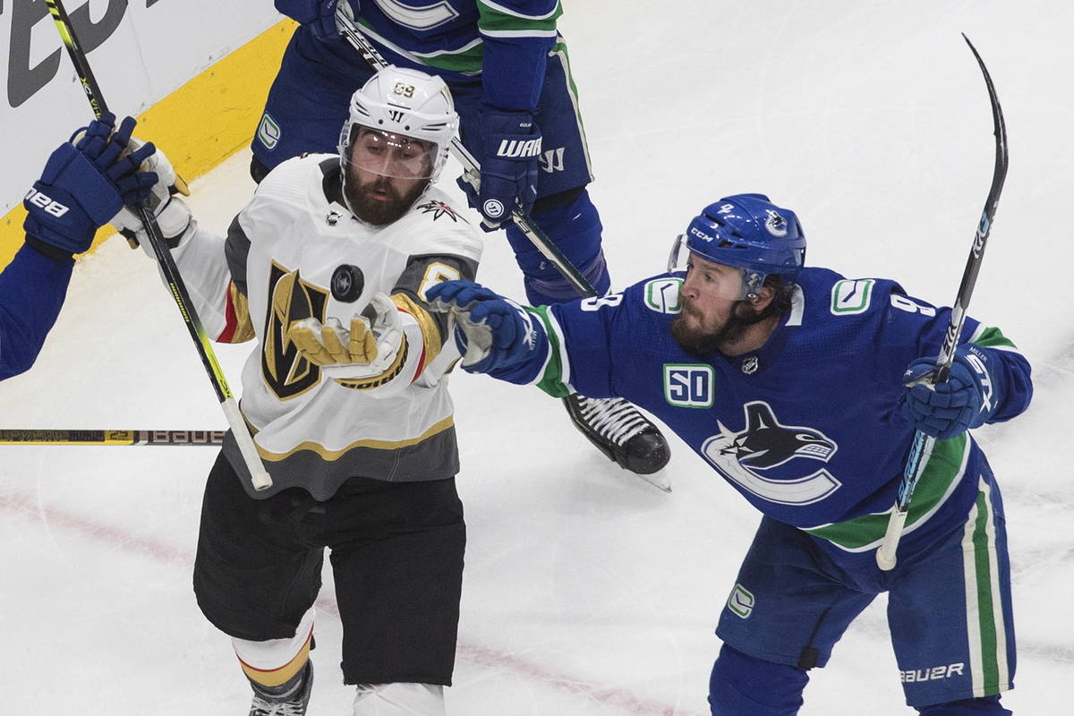 Vancouver Canucks' J.T. Miller (9) and Vegas Golden Knights' Alex Tuch (89) reach for the puck ...