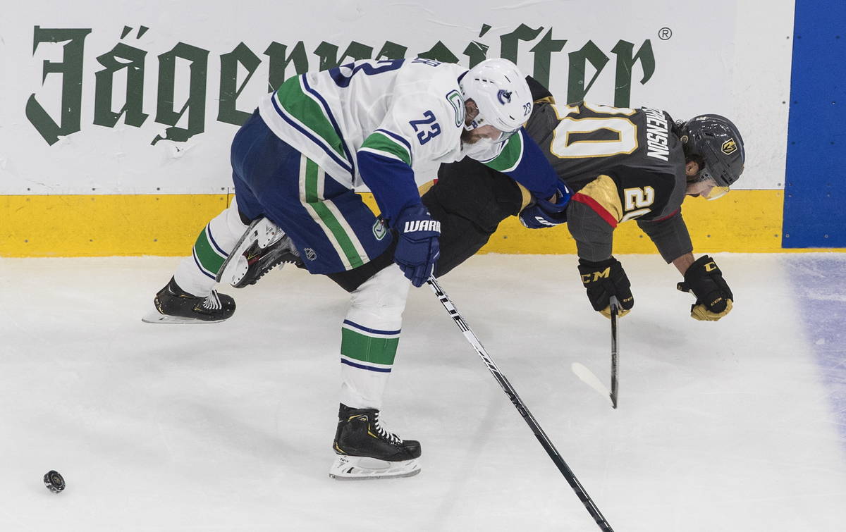 Vancouver Canucks' Alexander Edler (23) checks Vegas Golden Knights' Chandler Stephenson (20) d ...