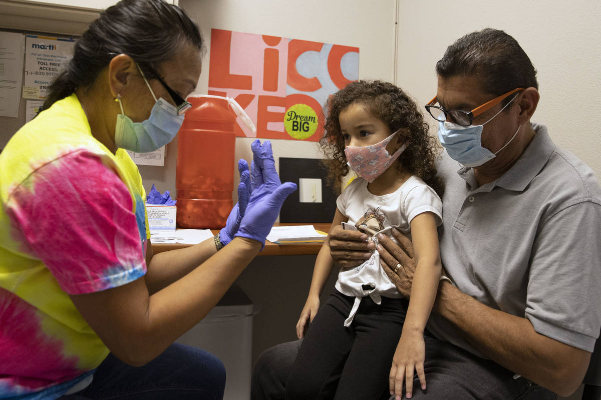 Roberto Lopez holds and his daughter Jasmin Moreno, 4, listen to Victoria Hodge, licensed pract ...