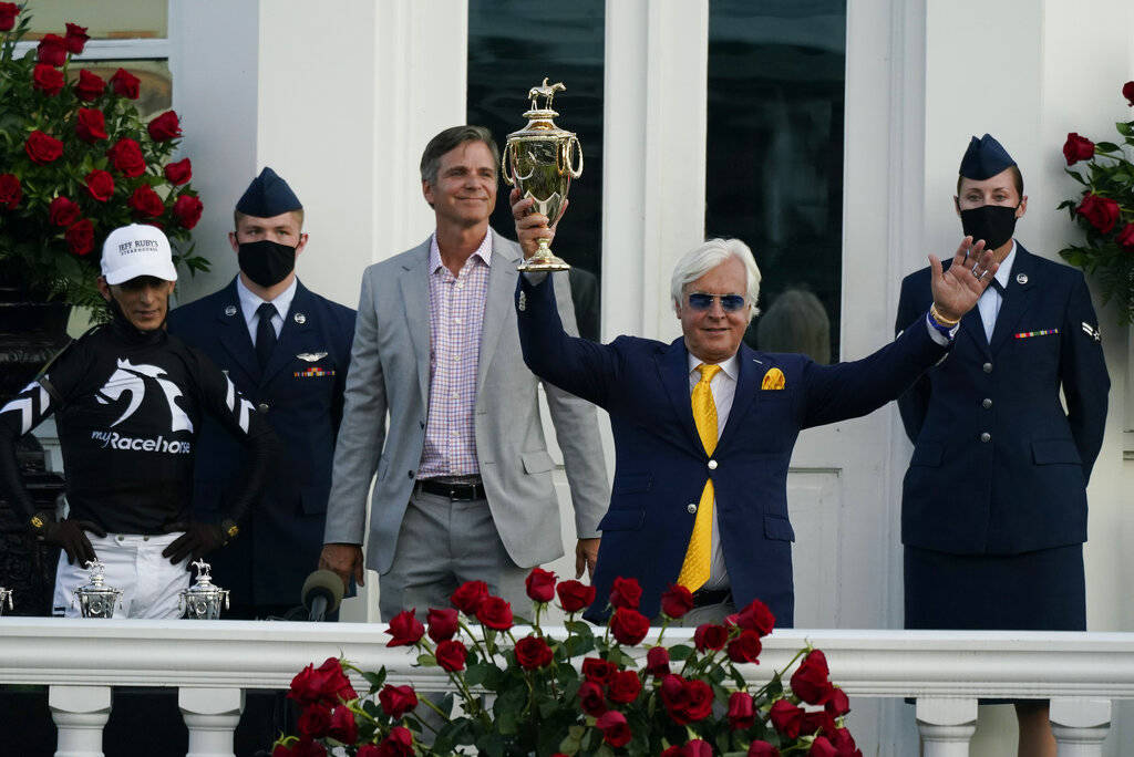 Trainer Bob Baffert holds the trophy after John Velazquez, left, rode Authentic to victory in t ...