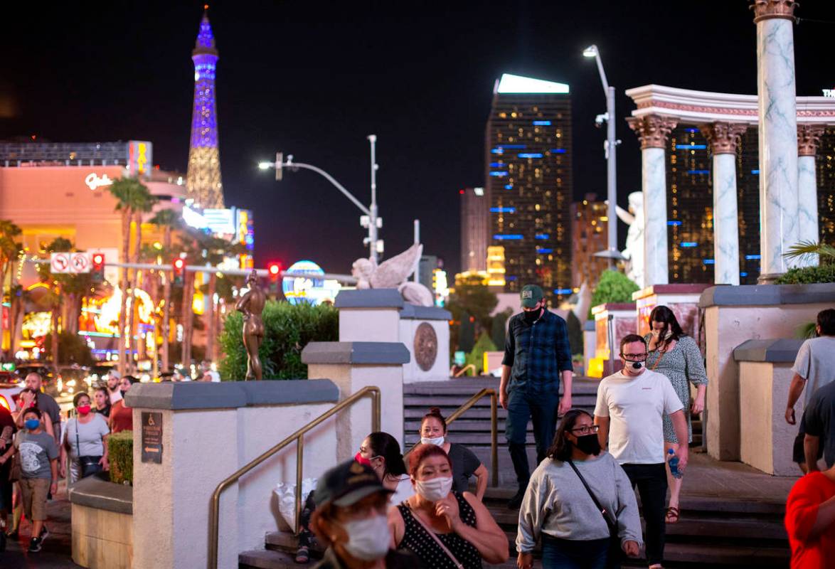 Some visitors wore masks while walking past Caesars Palace on the Strip while others refrained ...