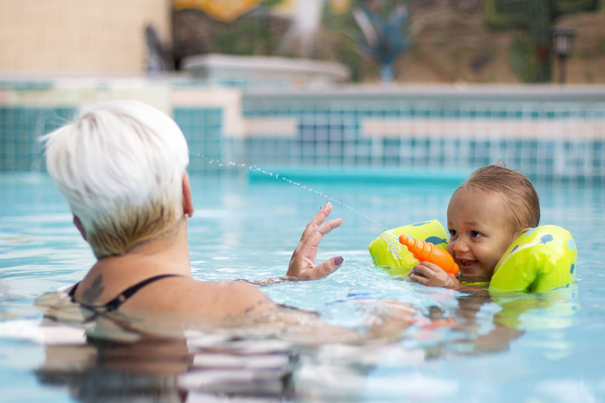 King Carter, 1, sprays his grandma, Tina Carter, with a squirt gun in their backyard pool on Su ...