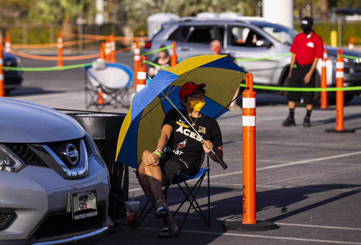 Las Vegas Aces fan Toni Jimenez, of Henderson, uses an umbrella while watching a drive-in showi ...