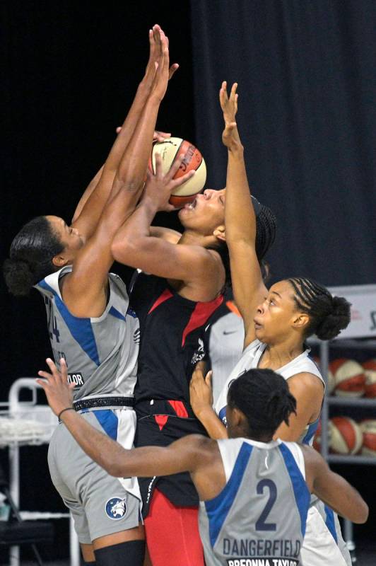 Las Vegas Aces center A'ja Wilson, center top, goes up to shoot between Minnesota Lynx forward ...