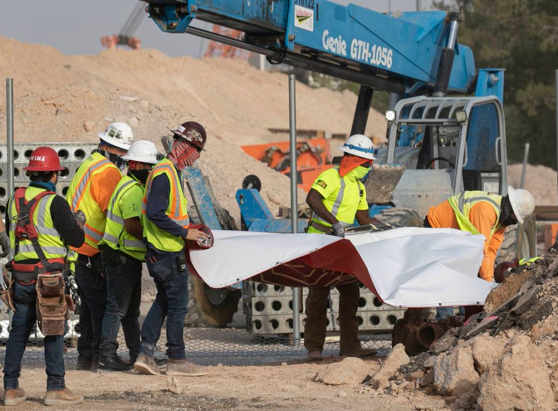 Construction workers try to recover the Resorts World construction site sign after heavy wind k ...