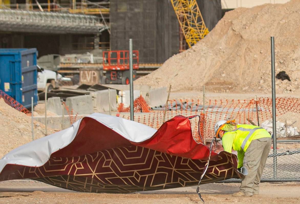 A construction worker tries to fold the Resorts World construction site sign after heavy wind k ...