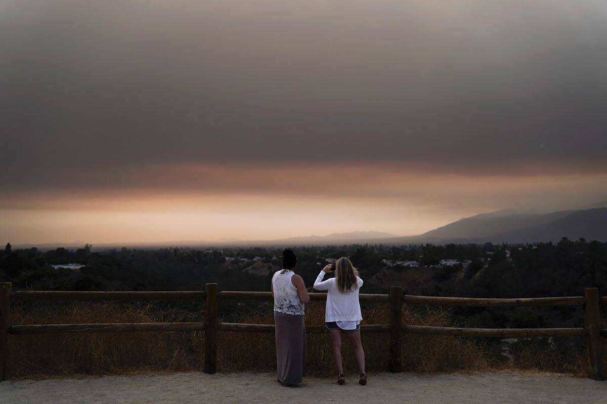 Two spectators watch smoke generated by the Bobcat Fire in San Dimas, Calif., Wednesday, Sept. ...