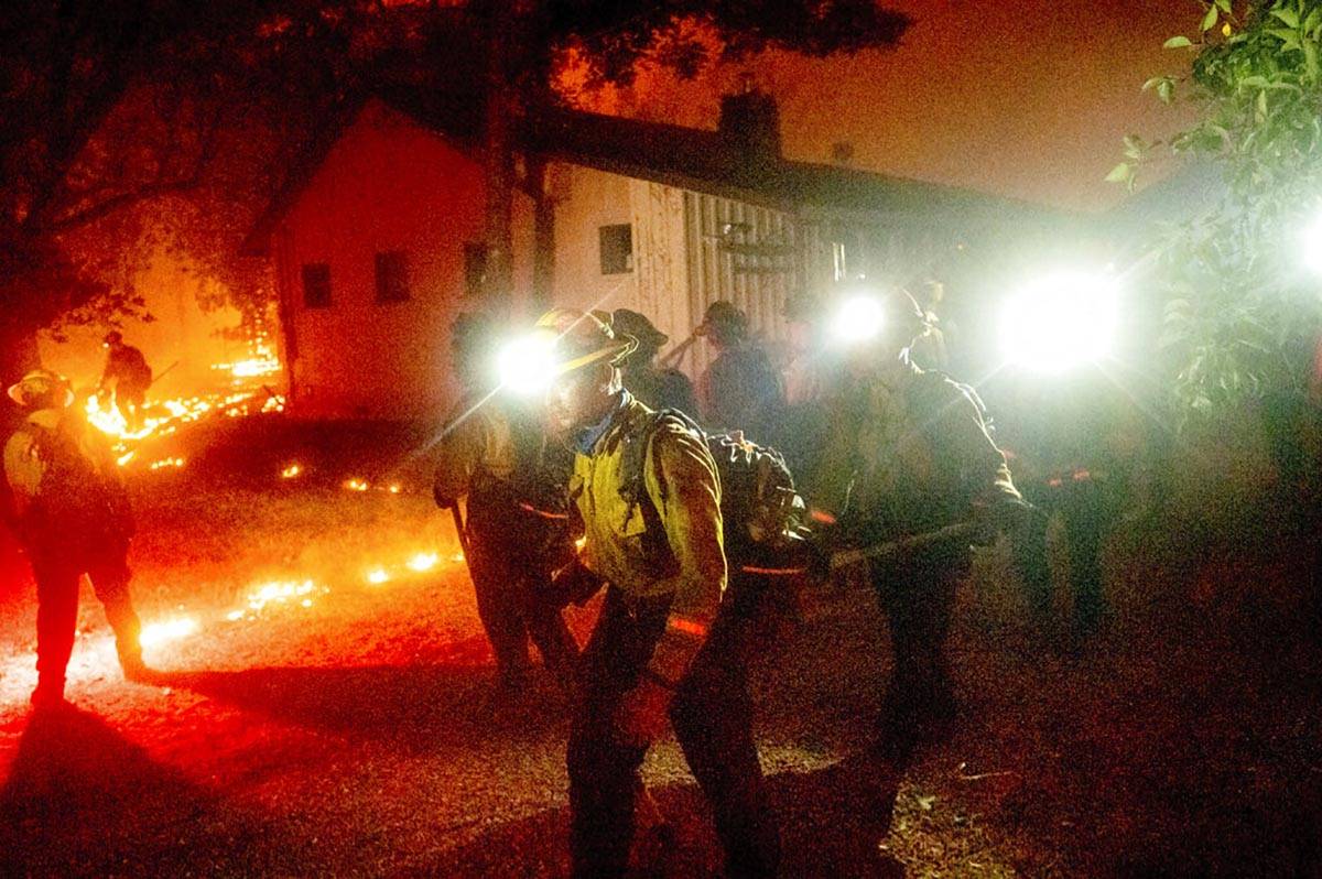 A hand crew works to save a home as the Bear Fire burns through the Berry Creek area of Butte C ...