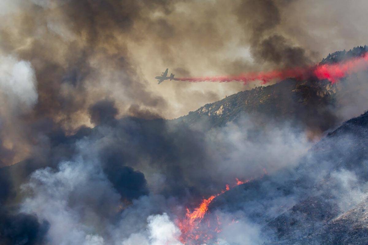 An air tanker drops retardant at a wildfire burns at a hillside in Yucaipa, Calif., Saturday, S ...