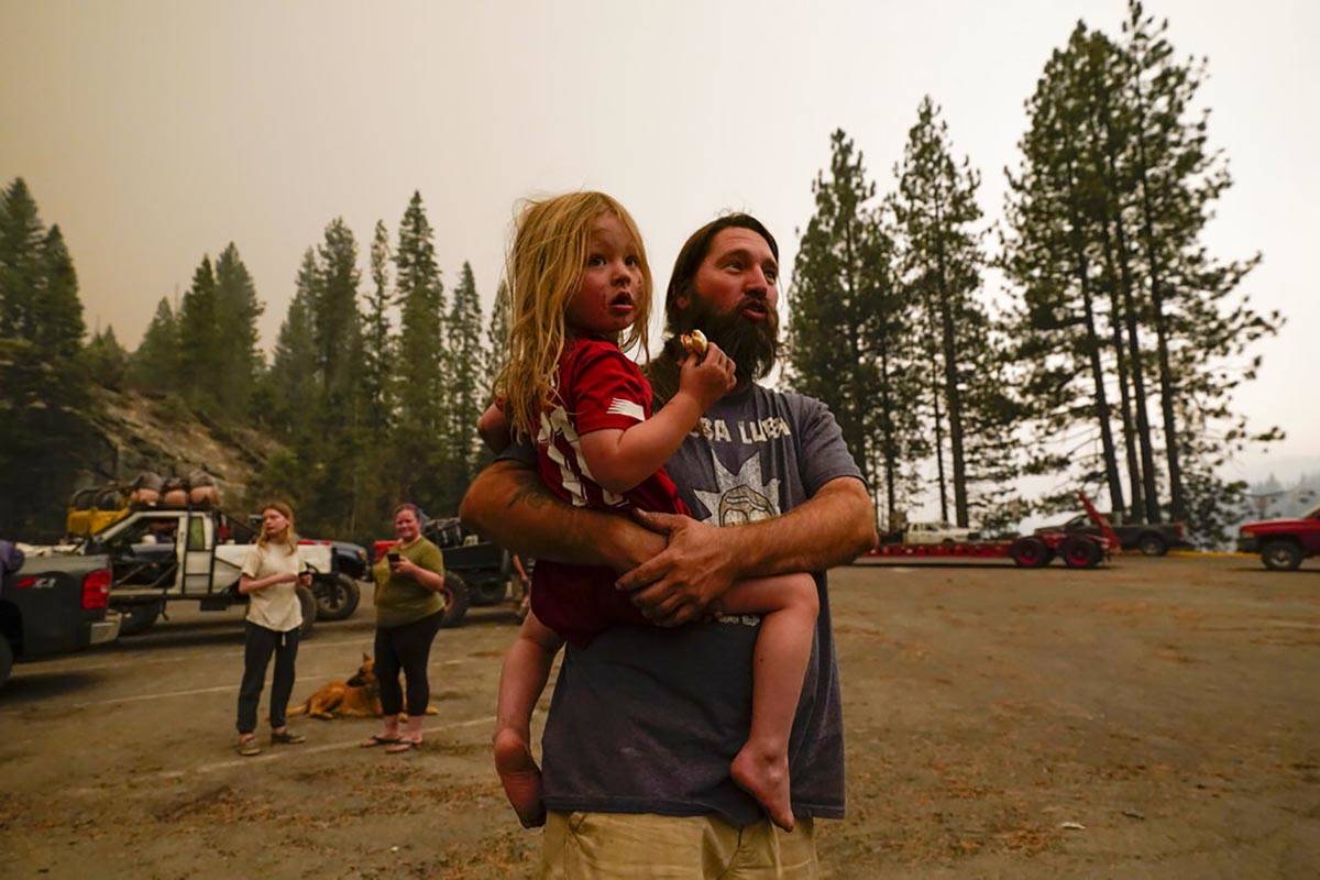 Jeremy Hedrick holds his son Jeep as smoke from the Creek Fire fills the air in a marina, were ...