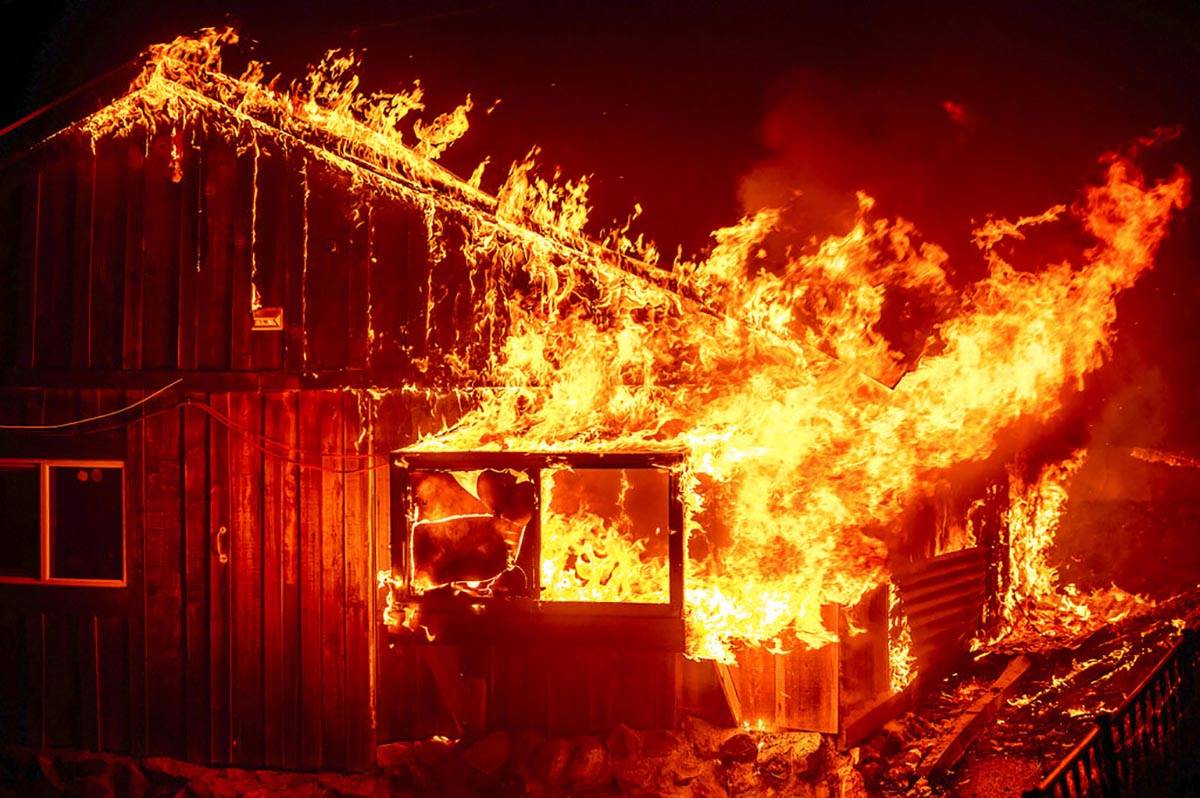 Flames shoot from a home as the Bear Fire burns through the Berry Creek area of Butte County, C ...