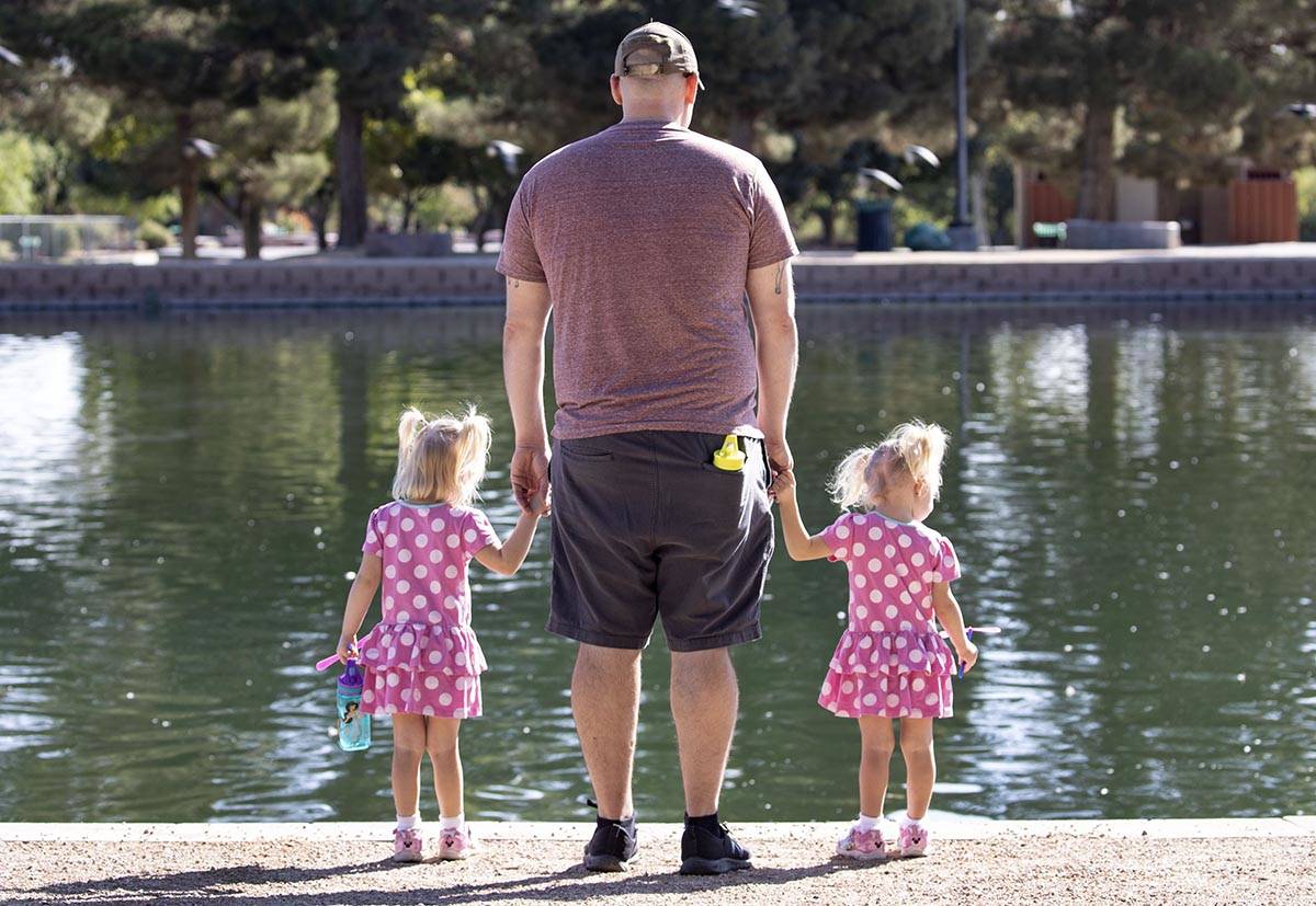 Derrick Agnew relaxes with his daughters Penelope, 3 , left, and Eloise, 2, at Sunset Park on T ...