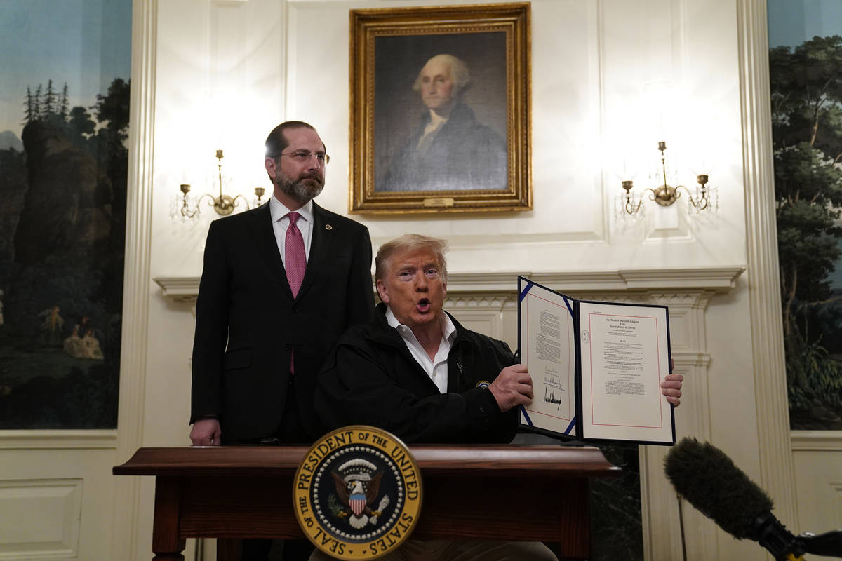 President Donald Trump holds up an $8.3 billion bill to fight the coronavirus outbreak in the U ...