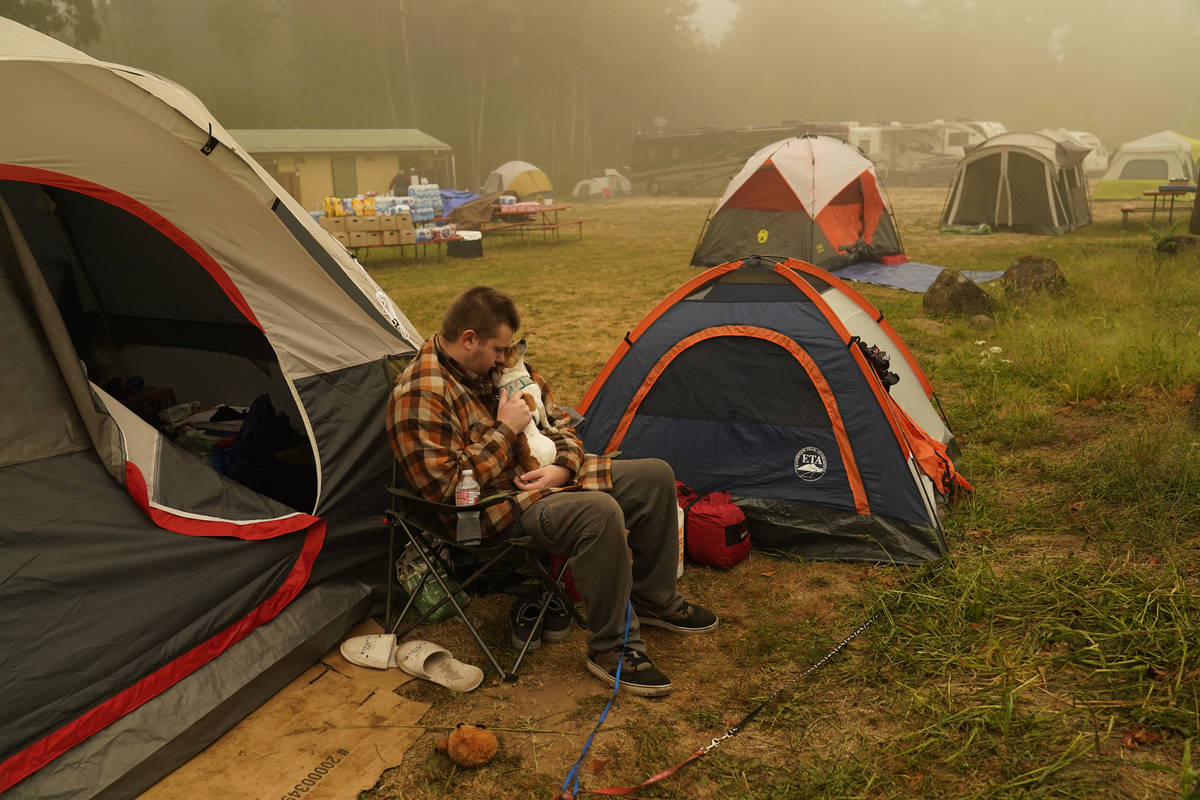 Kristopher Smith holds his dog Tripp outside his tent at an evacuation center at the Milwaukie- ...